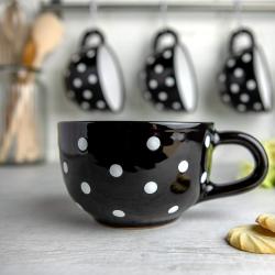 Tasse en céramique noire, pois blancs, artisanale en situation